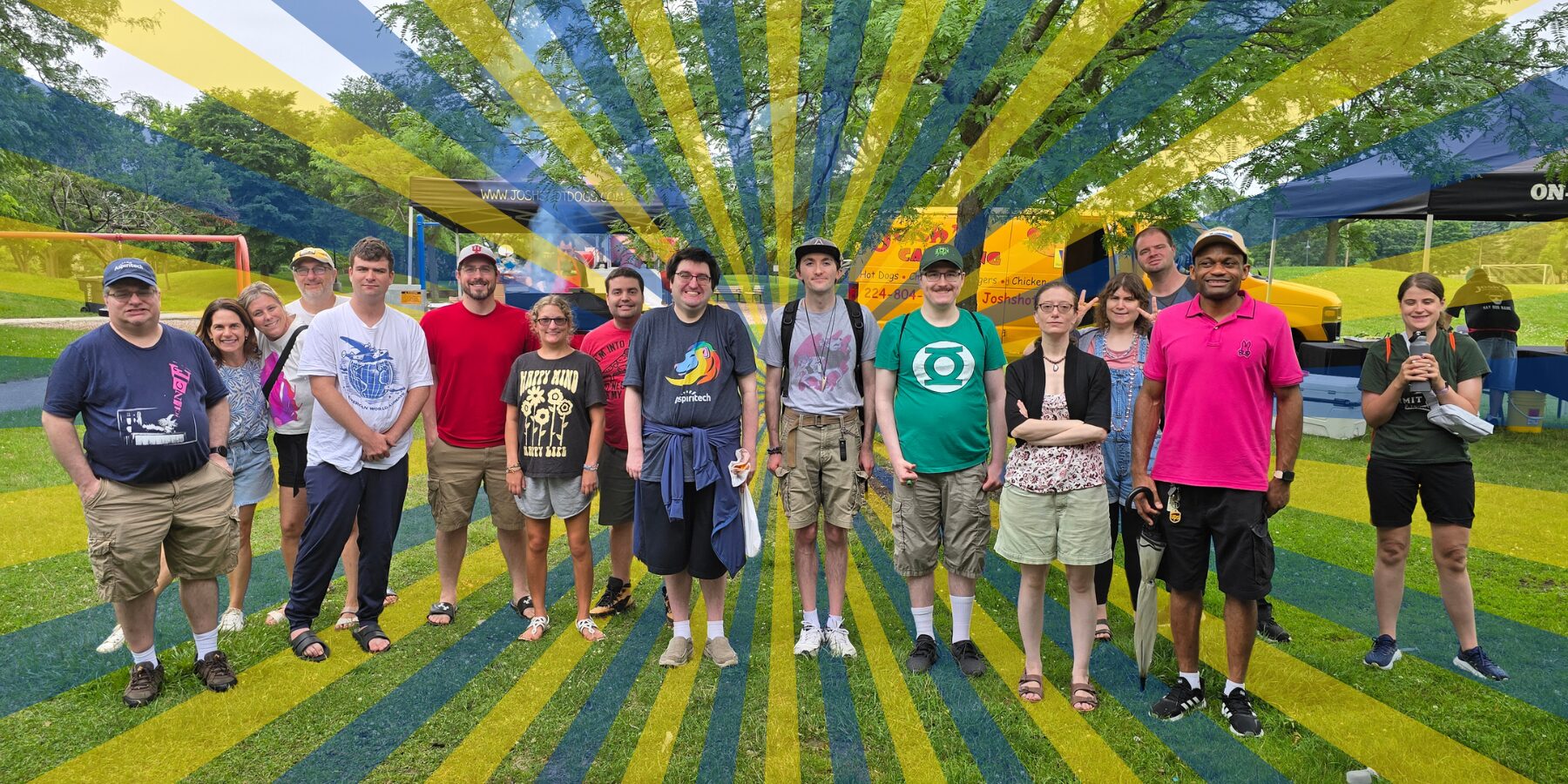 Sixteen Aspiritech team members and Stepping Up & Out program participants take a group photo during our annual summer picnic. A graphic of expanding blue and yellow rays decorates the background.