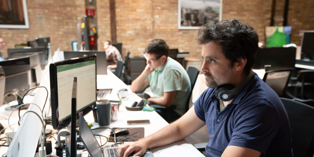 several employees at a long desk focused intently on their computers.