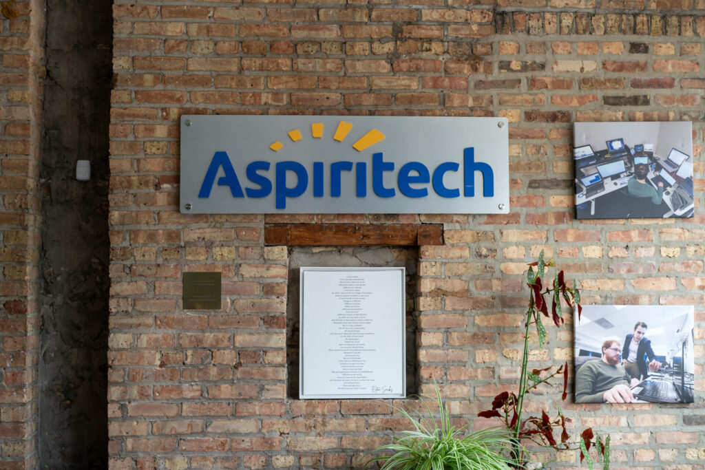 A brick wall adorned with the Aspiritech logo.