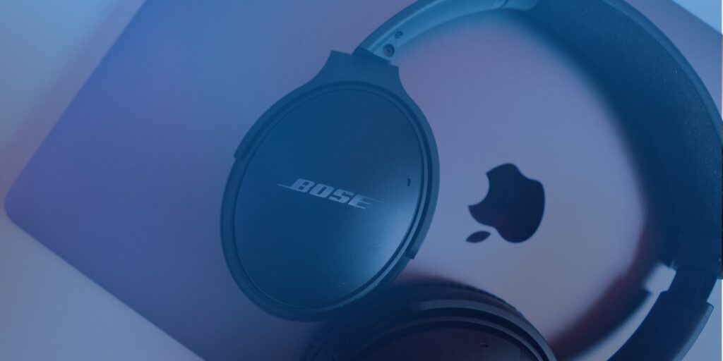 Bose headphones rest on an Apple laptop.