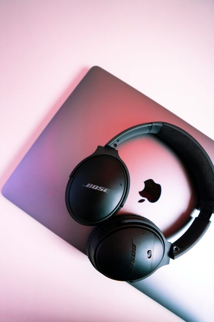Bose headphones rest on a gradient pink Apple laptop.