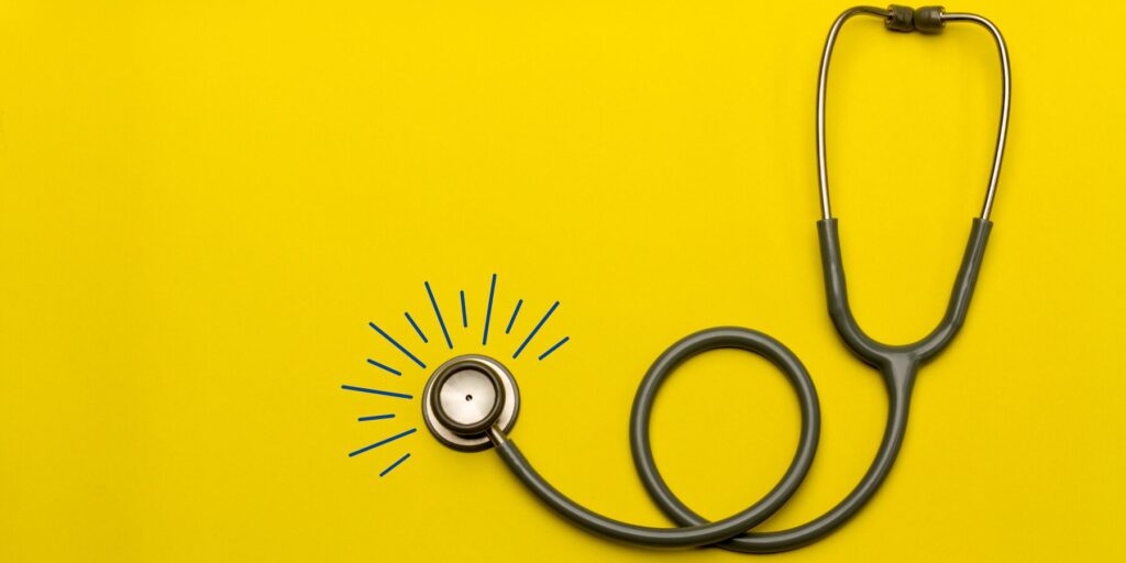 A black stethoscope on a bright yellow surface.