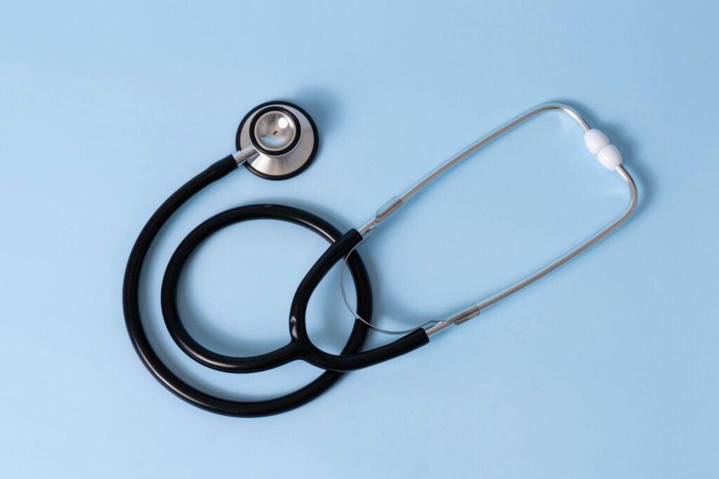 A black stethoscope lies against a pale blue background.