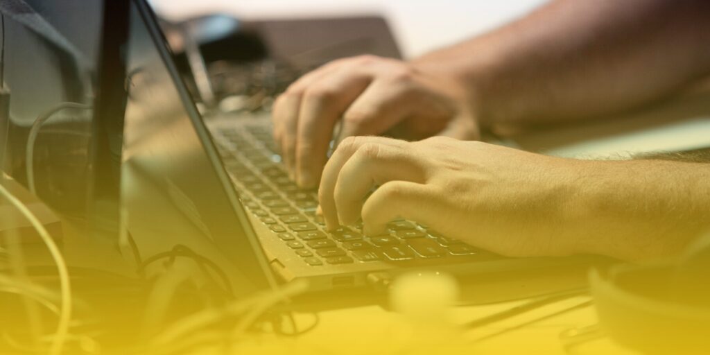 Hands work at a laptop keyboard.