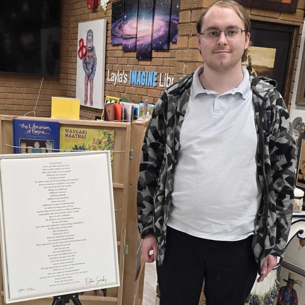 Eitan Sacks stands beside a print of his poem inside the International Servant Leaders Museum.