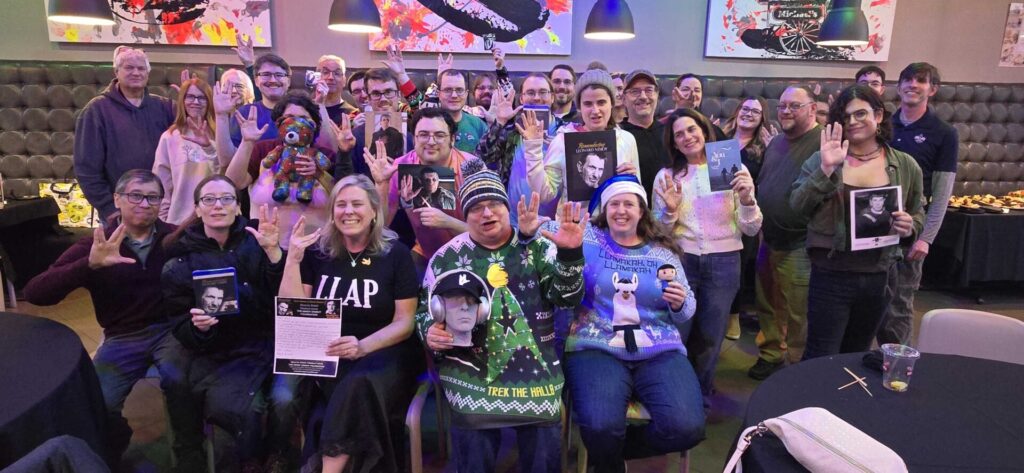 A large group of Aspiritech team members and friends doing the Vulcan salute hand gesture at our 2025 holiday party.