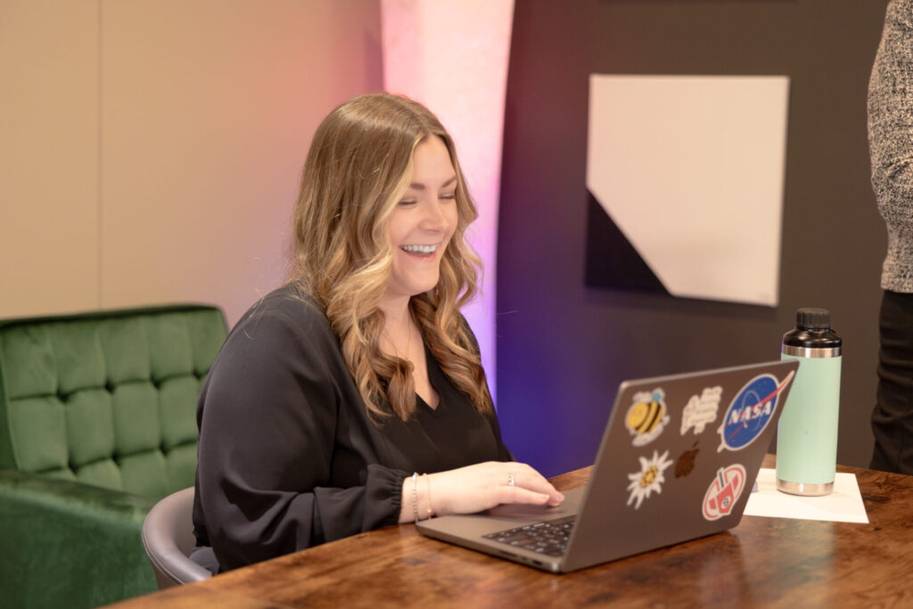 A female Aspiritech employee smiles while working at a laptop.