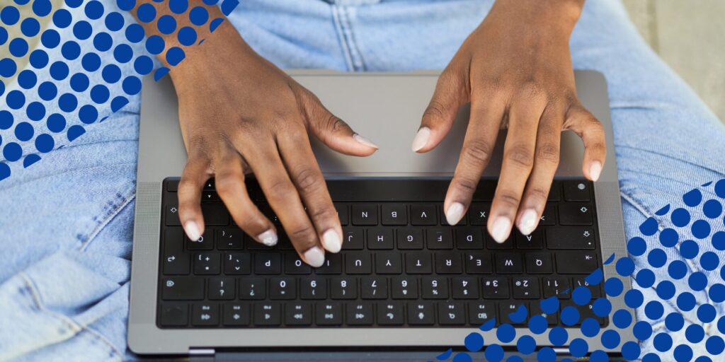 A person's hands type on a laptop keyboard.