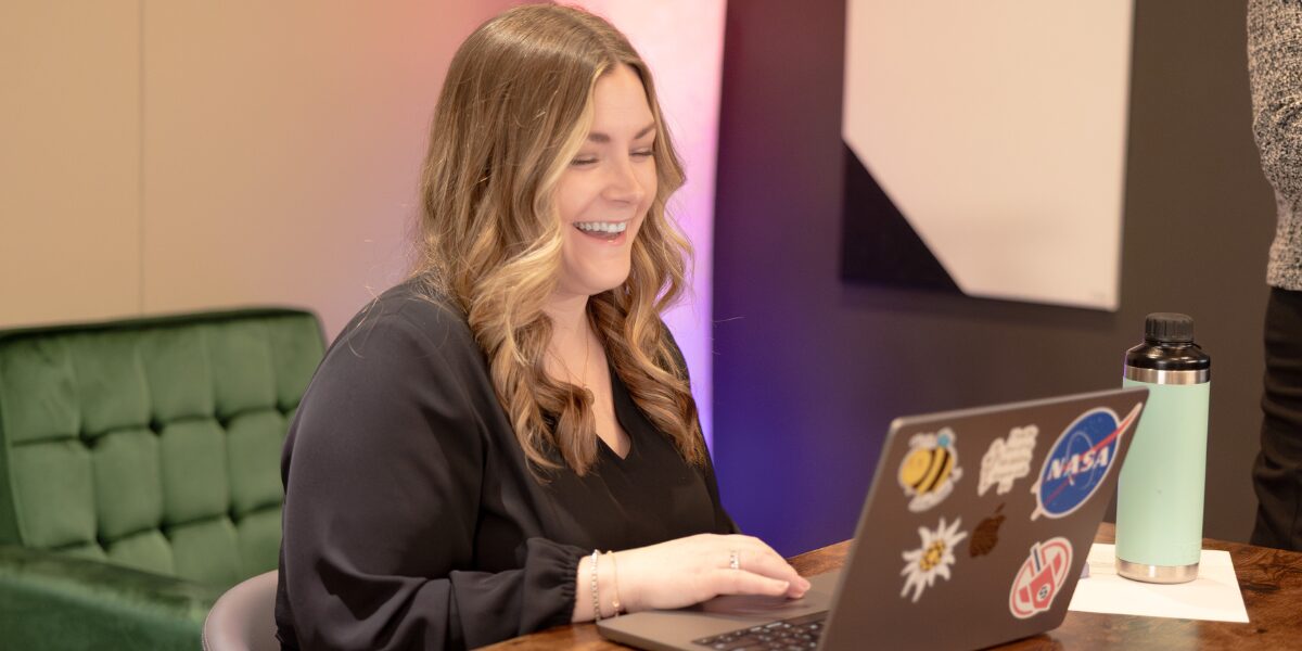 A female Aspiritech employee smiles while working at a laptop.
