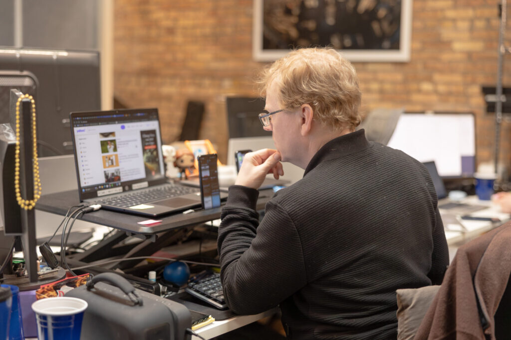 A male Aspiritech employee ponders while looking at a laptop.