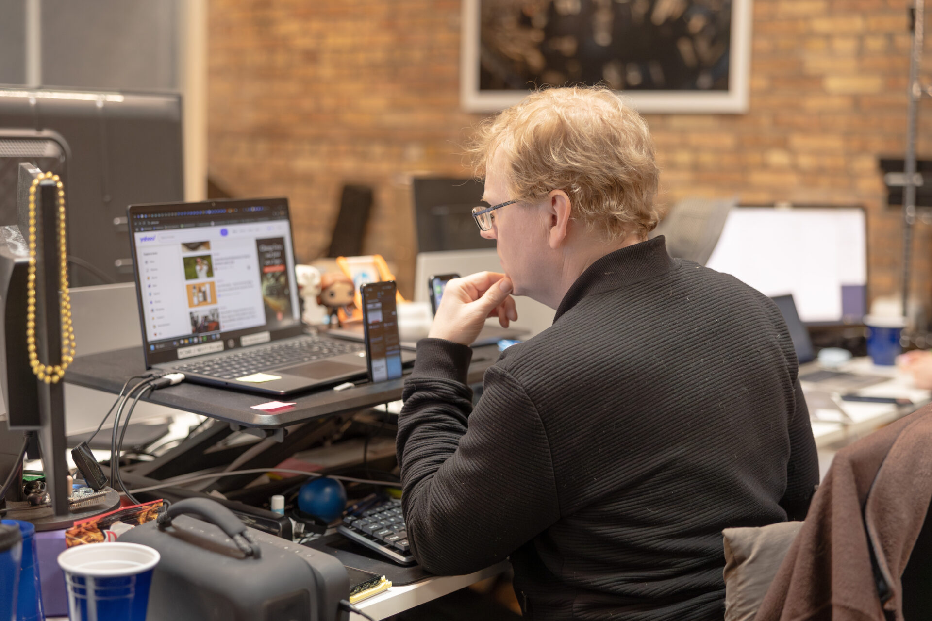 A male Aspiritech employee ponders while looking at a laptop.