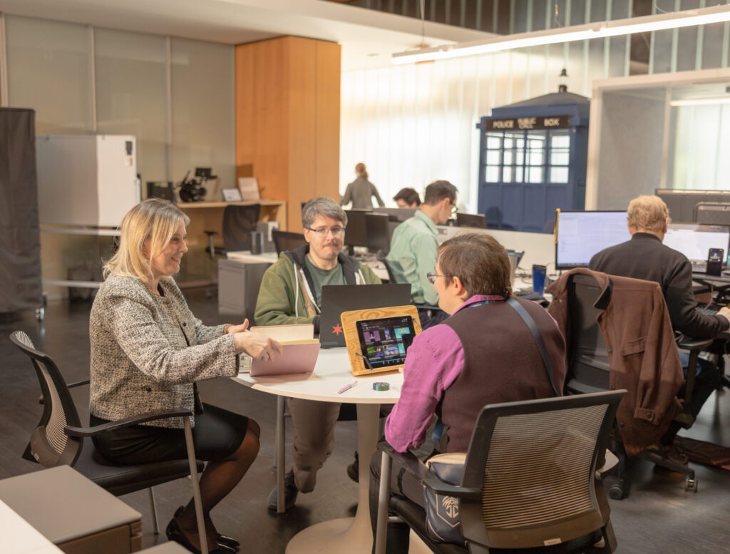 Aspiritech team members work at a table in an open office space.
