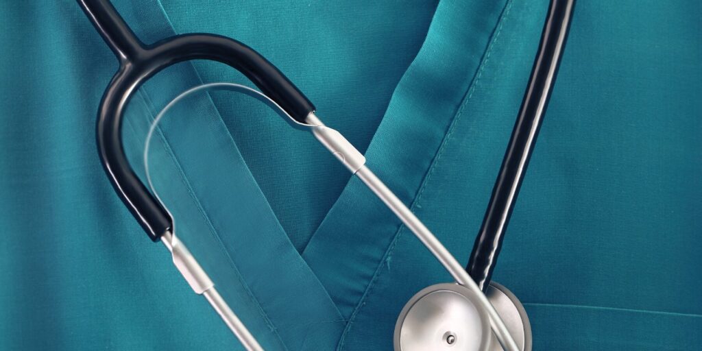A closeup of a stethoscope against turquoise blue scrubs.